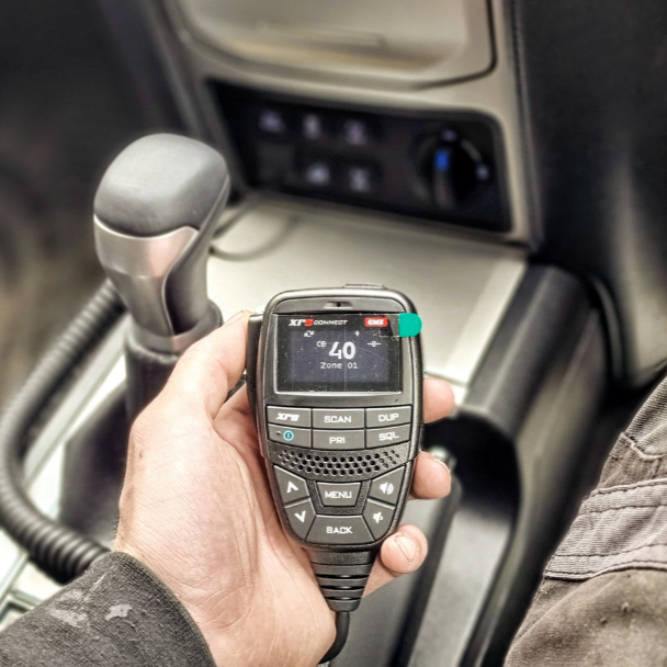 Hands steering a car with a navigation map on the display, driving with sunlight in the background.