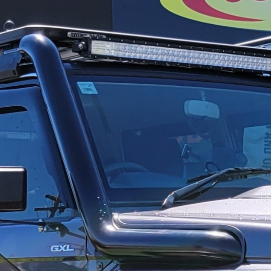 White truck with a black snorkel on the side, parked outdoors on a sunny day.