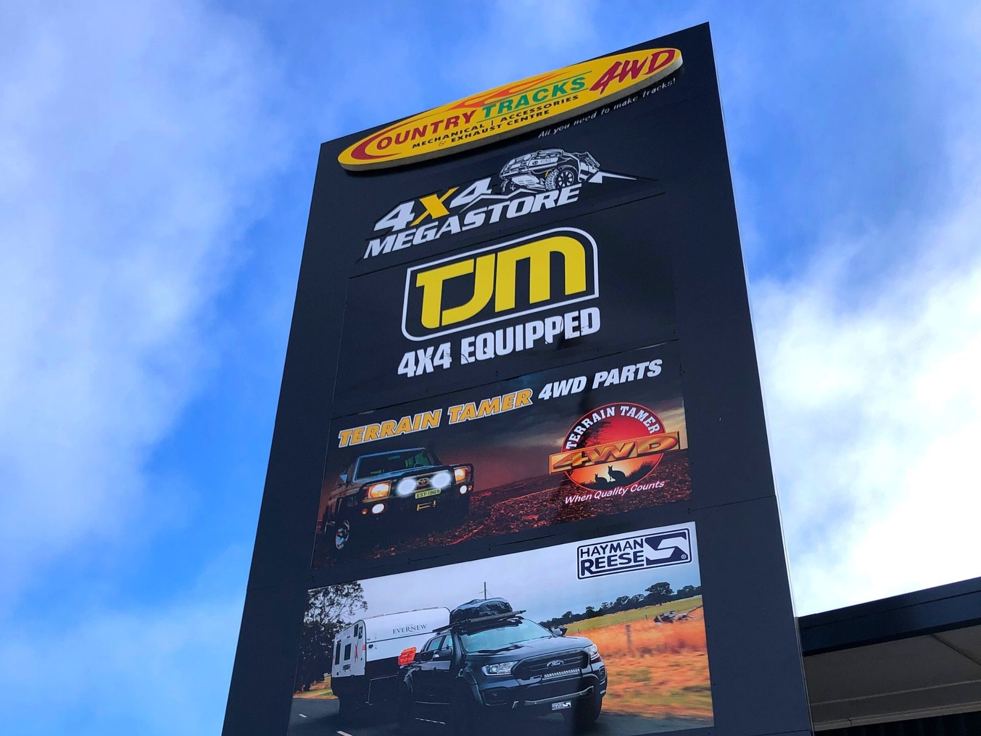 Two men in a store holding a hat and photo, behind a vehicle protection display.