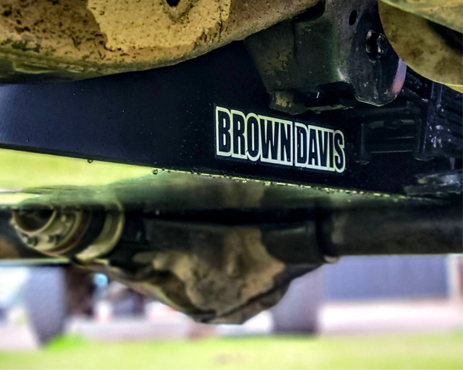 Undercarriage of a black vehicle with exhaust, fuel tank, and tires visible.