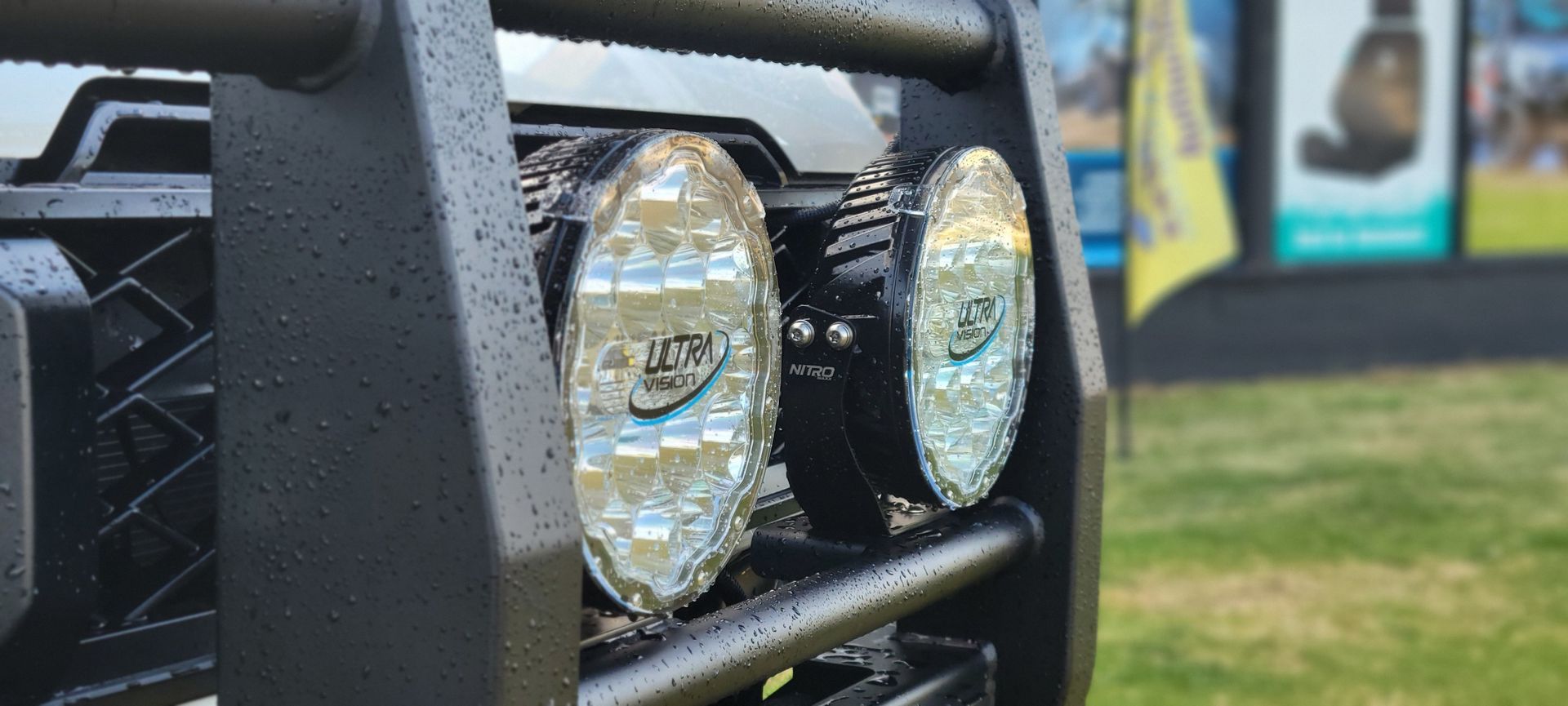 Car headlights illuminating a dark, tree-lined road at night.