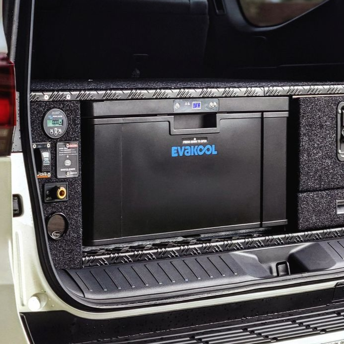 Person opening a black cooler with a white lid, two blue ice packs visible, outdoors on a bench.