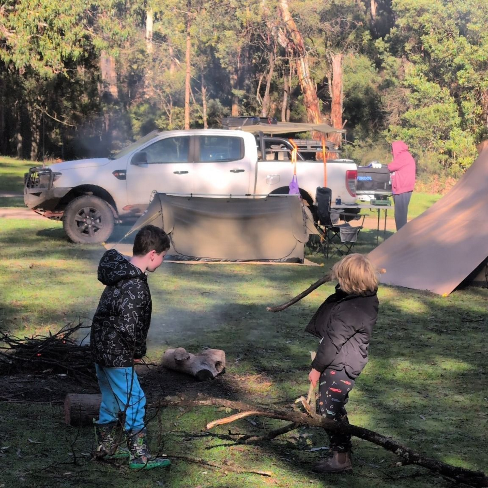 Silver off-road SUV on a dirt track; it has spotlights, a bull bar and is near a black sign.