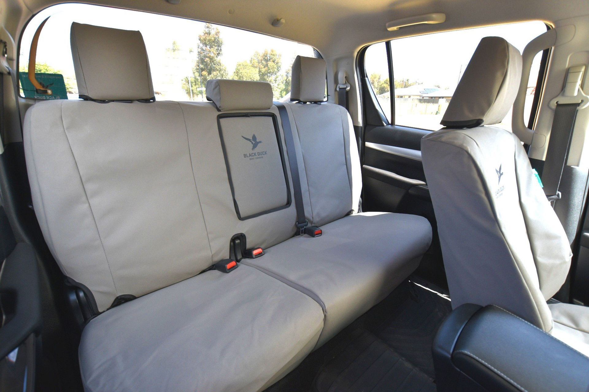 Tan rear truck seats with headrests and seat covers, featuring a logo on the center backrest.