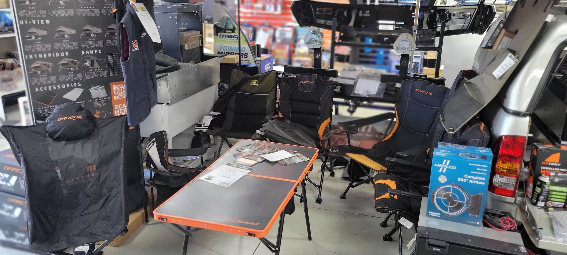 Woman and child camping near van, setting table in grassy field at sunset.