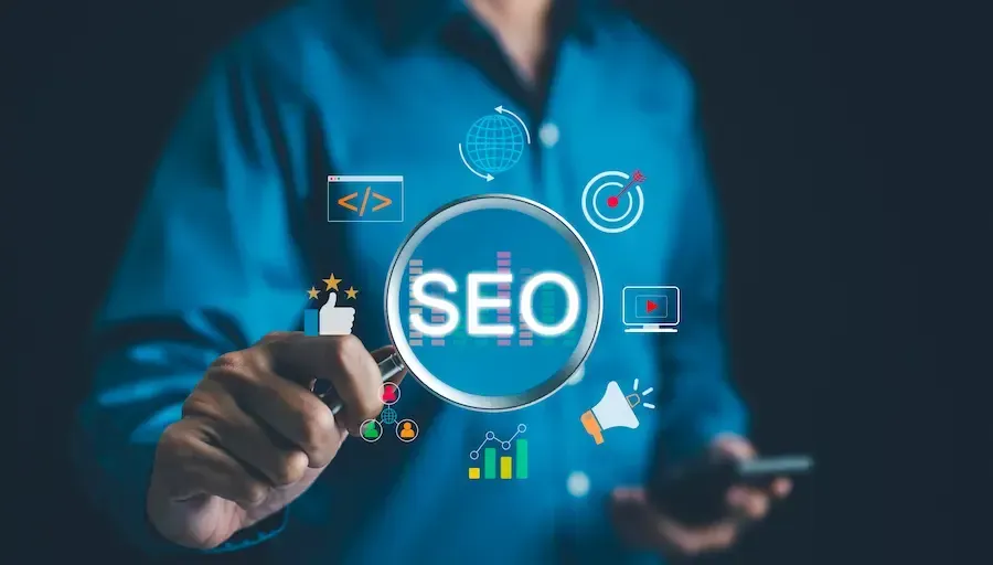 Person holding a magnifying glass that says SEO in it, with other aspects of SEO services around it.