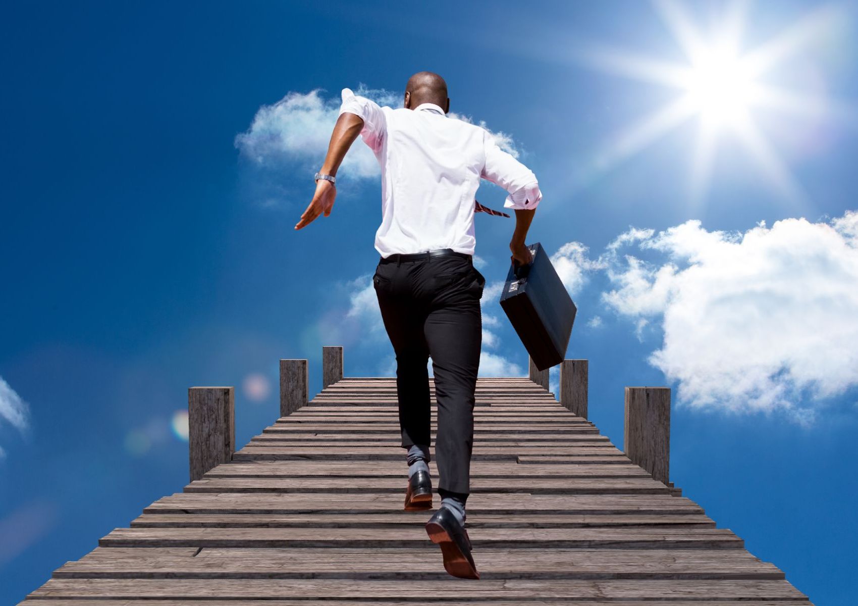 Business man with his briefcase running on the bridge to success in the sky. Florida Coast SEO is your bridge to success.