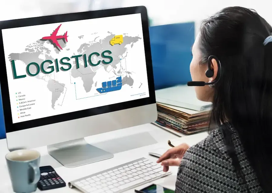 Woman on a computer with earpiece doing e-commerce logistics.