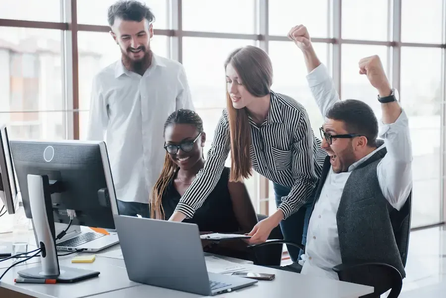 Happy Florida Coast SEO clients in front of computers. One man has his hands raised up.