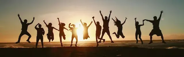 People jumping in the air by the ocean at sunset. Thriving from e-commerce services.