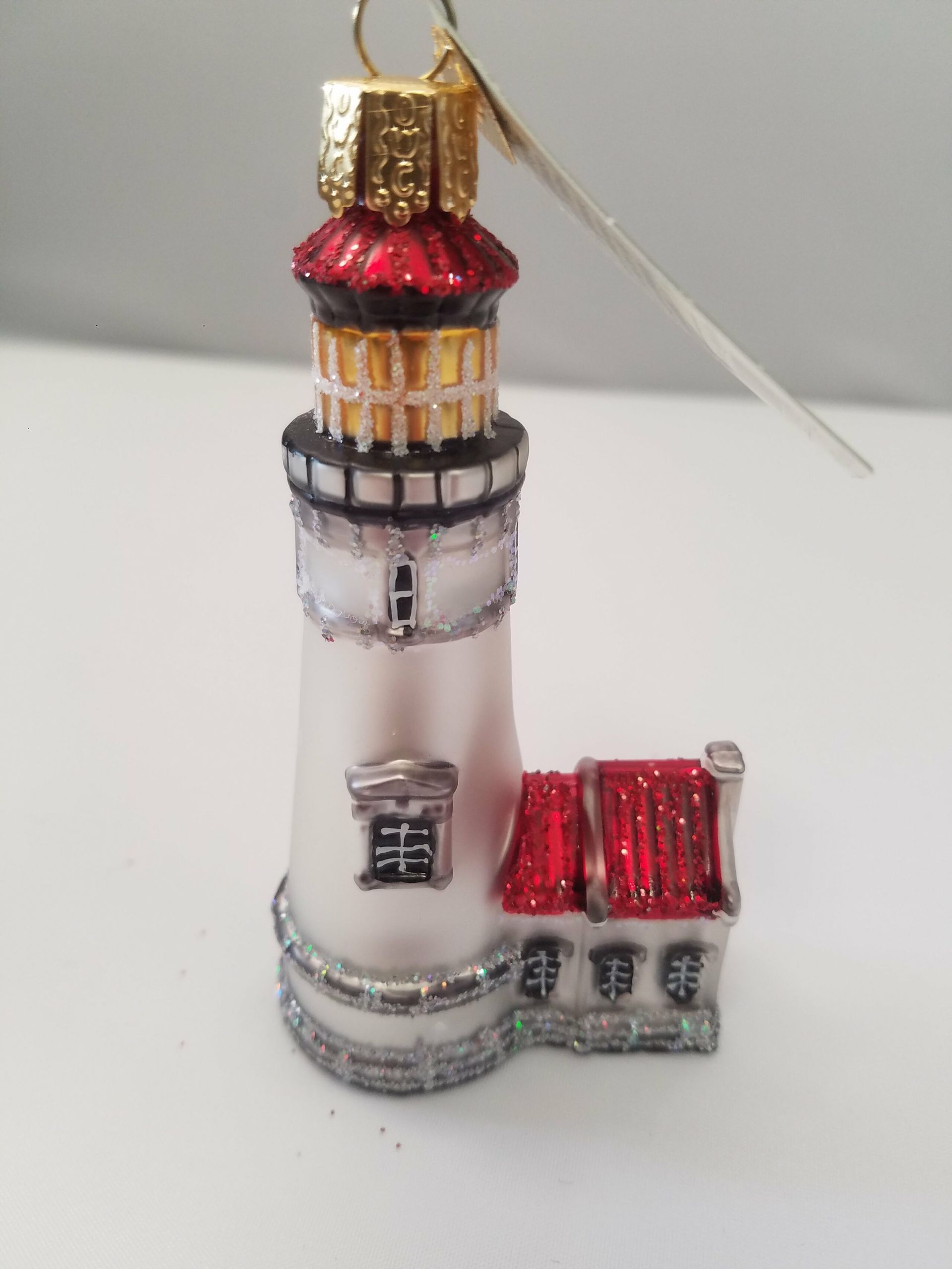A christmas ornament of a lighthouse with a red roof