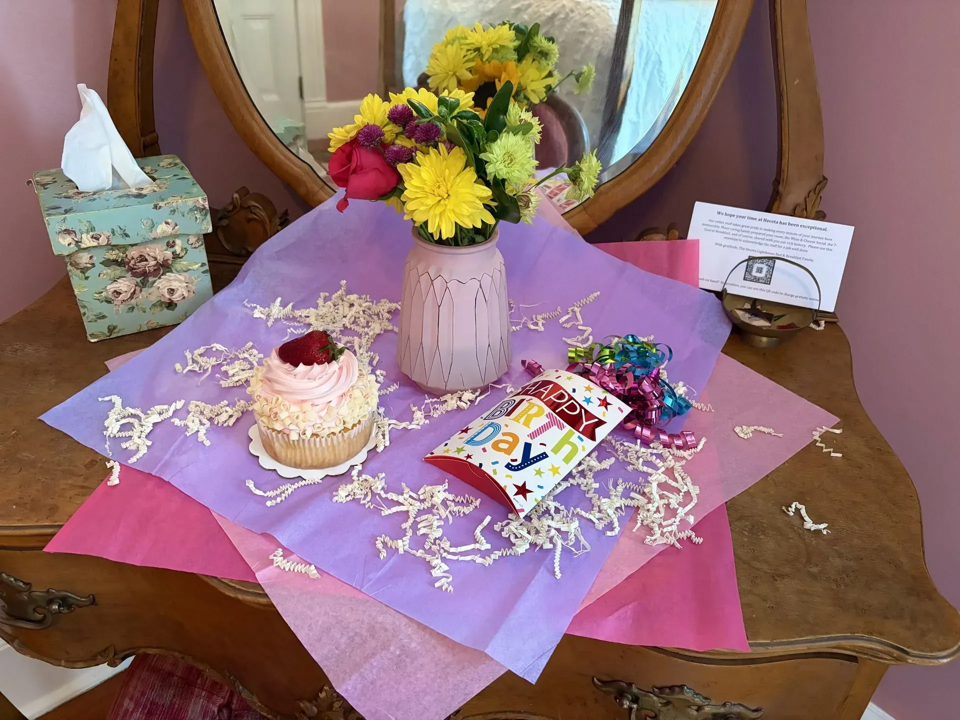 A picnic table with a bottle of wine , glasses , cheese , and a bag.