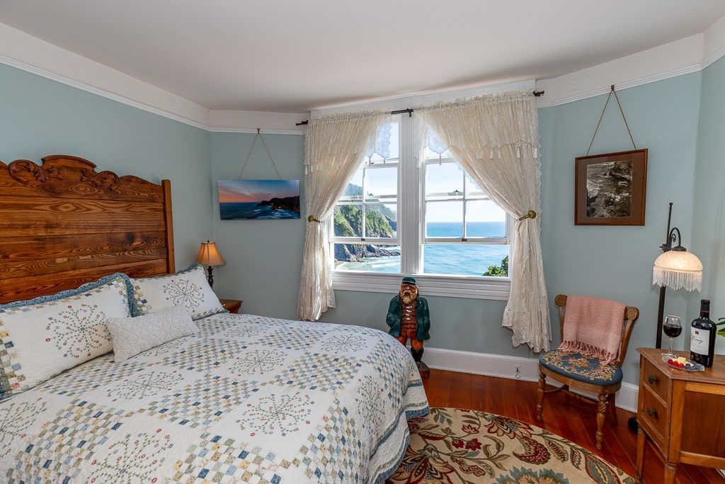 A bedroom with a large bed , a chair , a table and a window.