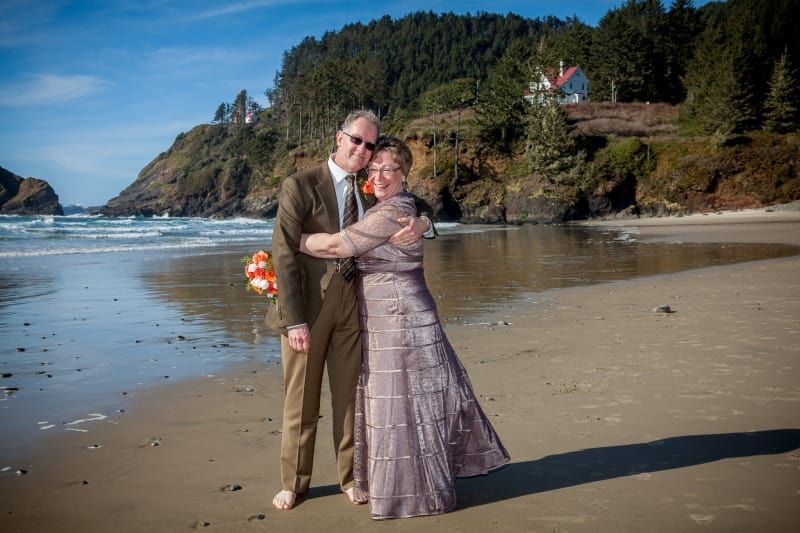 A bride and groom are posing for a picture on the beach.