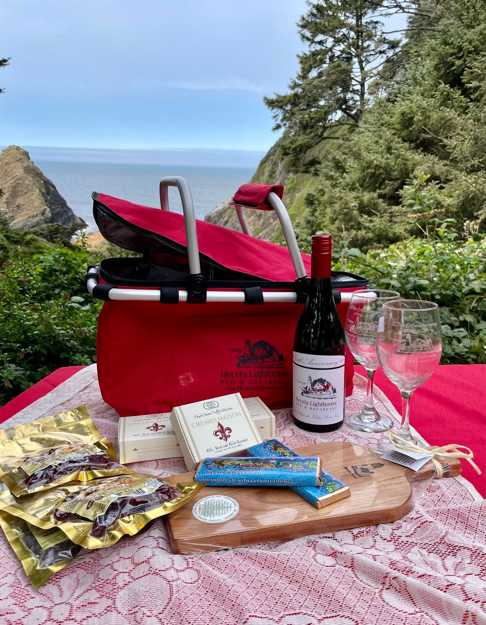 There is a picnic basket with a bottle of wine and a glass of wine on the table.