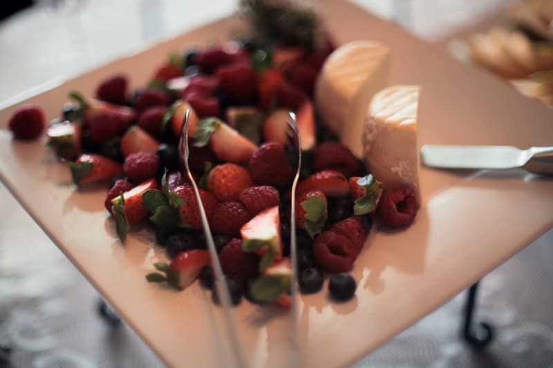 A white plate topped with strawberries , raspberries , blueberries and cheese.