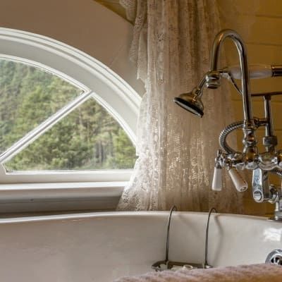 A bathtub with a shower head and a window in the background.