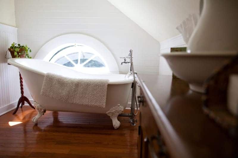 A bathroom with a claw foot tub and a window.