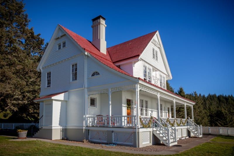 A large white house with a red roof and a porch.