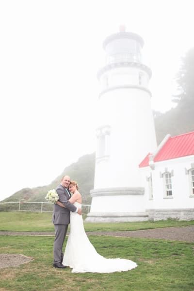 A bride and groom are posing for a picture in front of a lighthouse.