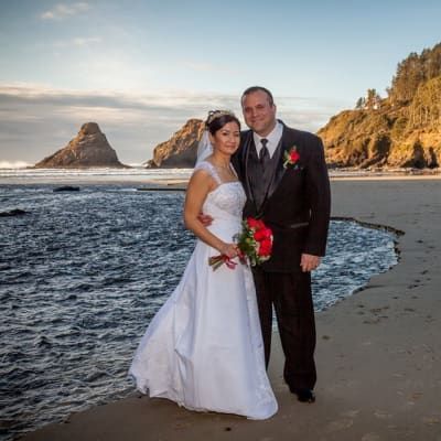 A bride and groom pose for a picture on the beach