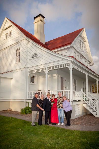 A group of people standing in front of a white house
