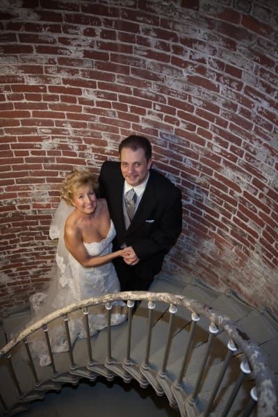 A bride and groom are posing for a picture on a spiral staircase.
