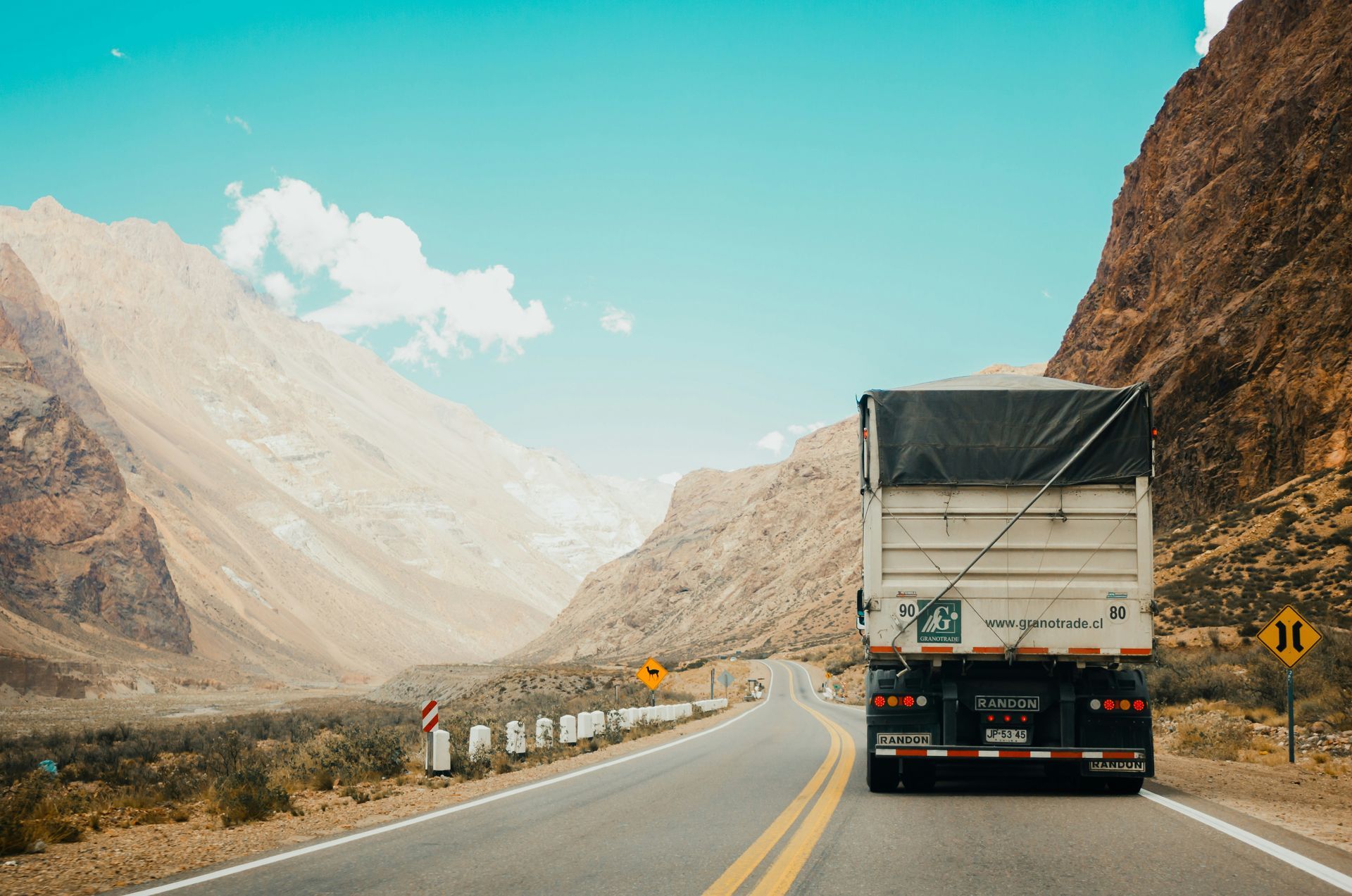 A white truck is driving down a mountain road.