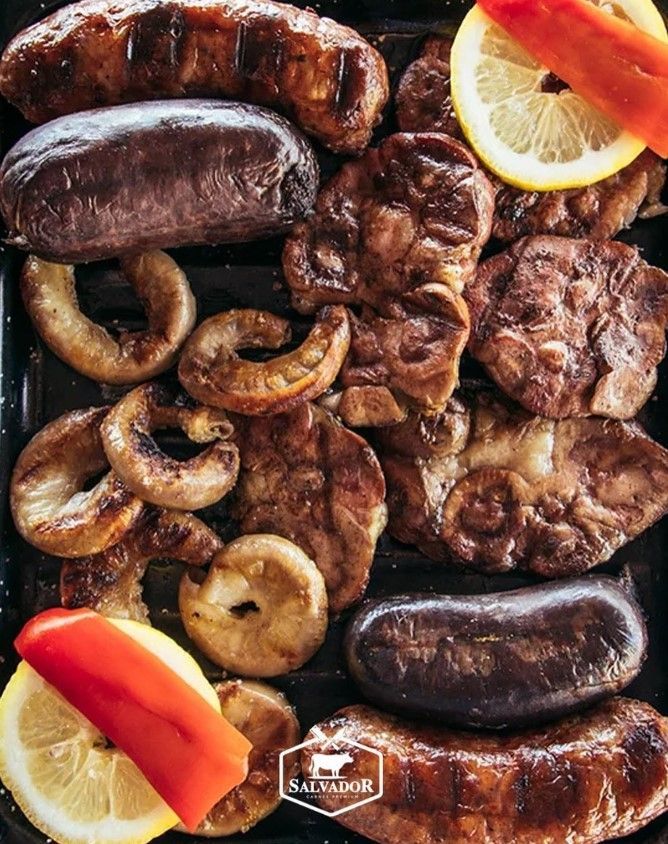 Una parrilla llena de muchos tipos diferentes de carne y verduras.
