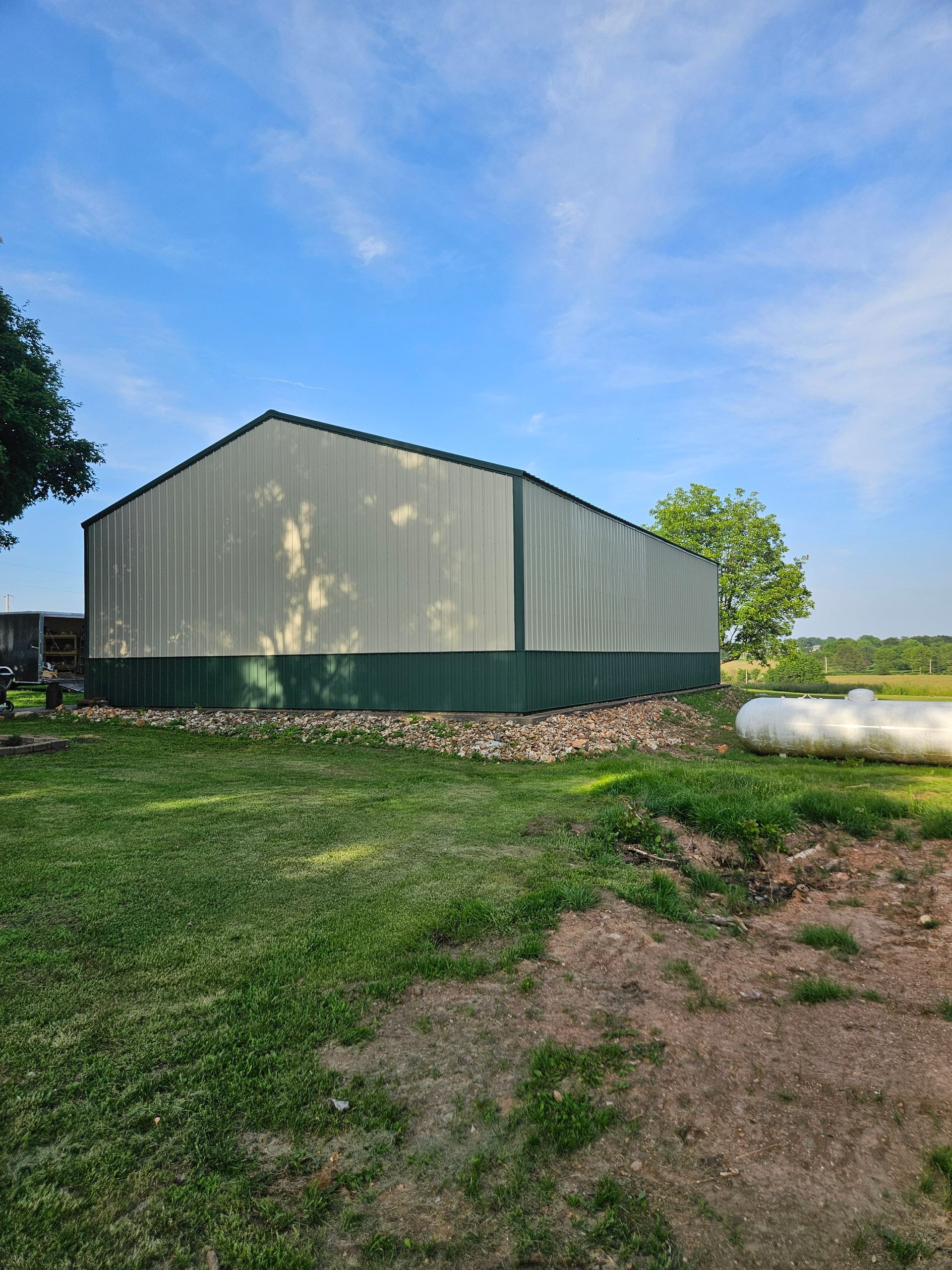 Large metal building with green trim, on a grassy area, with blue sky.