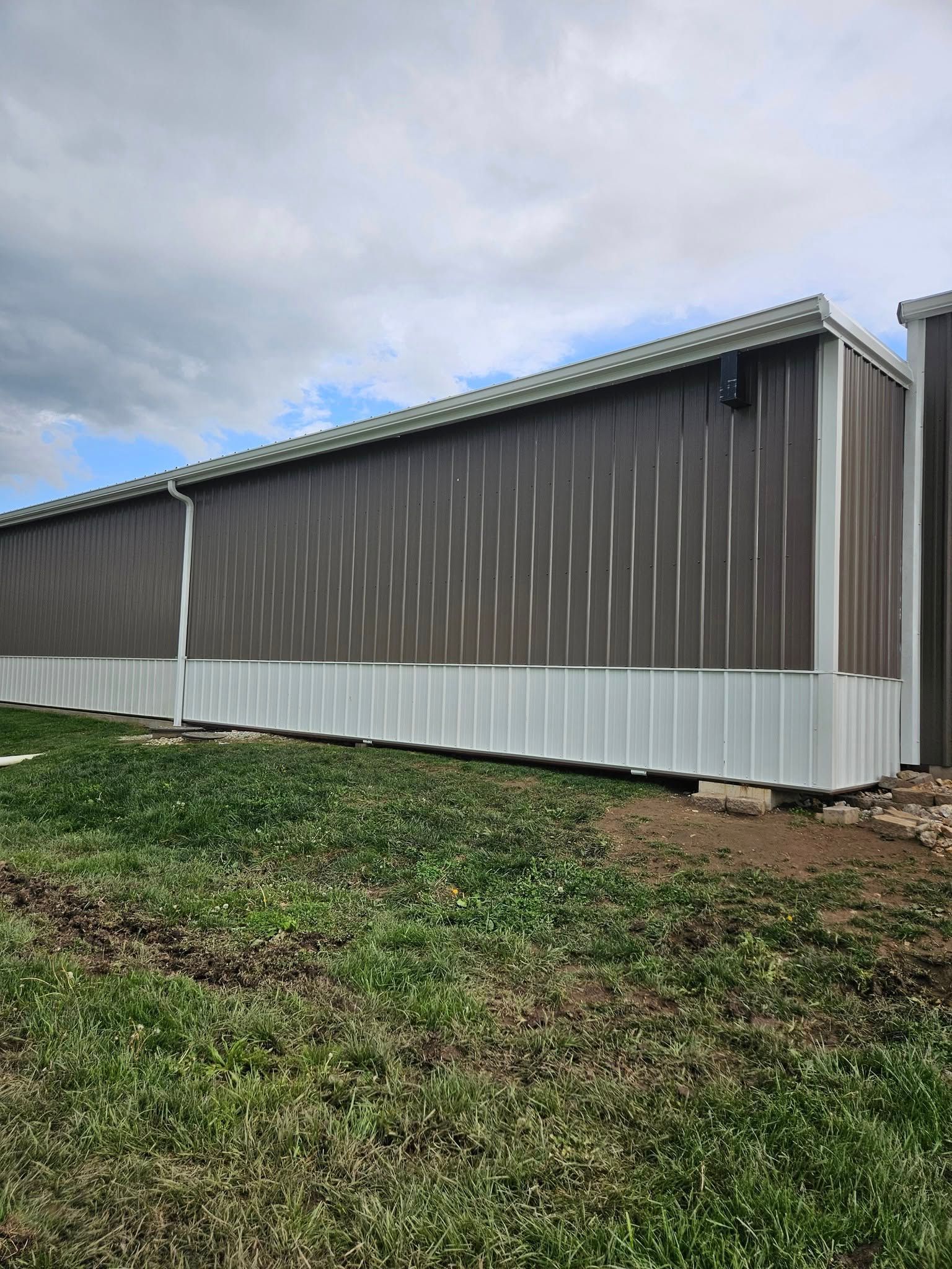 Long brown and white metal storage buildings, against a cloudy sky.