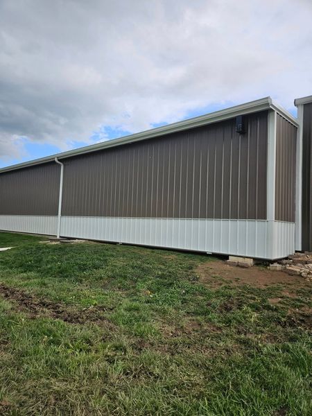 Long brown and white metal storage buildings, against a cloudy sky.