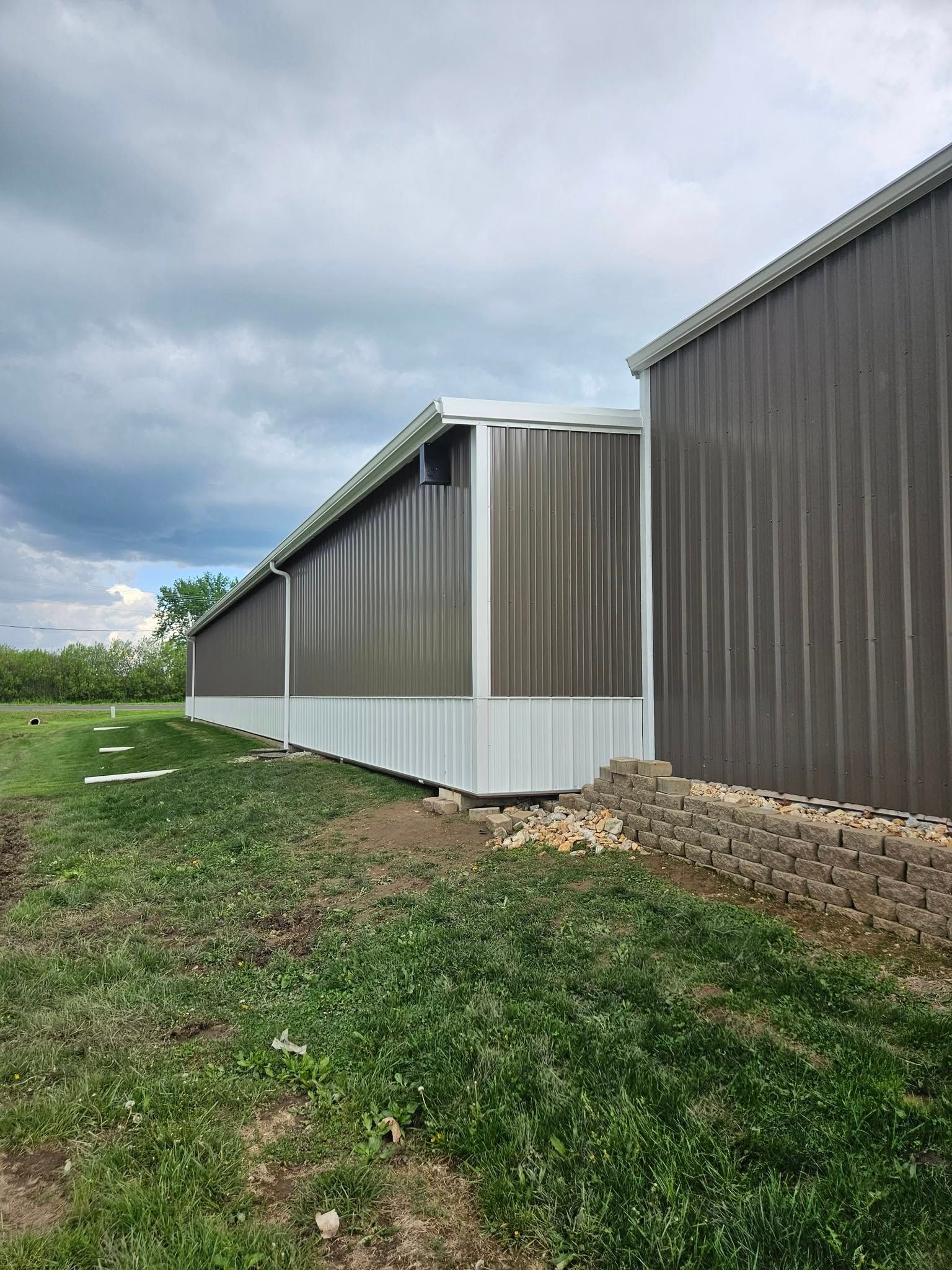 Brown and white metal building with a cloudy sky.