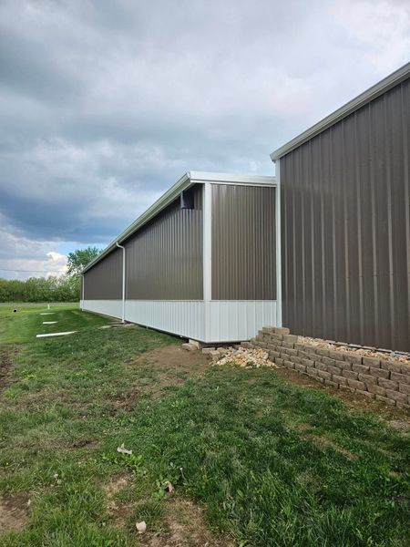 Brown and white metal building with a cloudy sky.