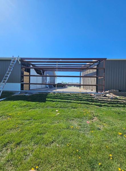 Steel frame structure under construction; blue sky background.
