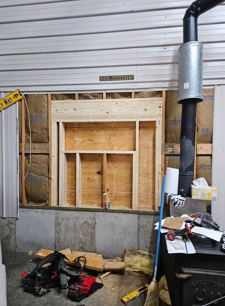Wall framing around a chimney with tools and insulation visible.