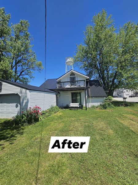 White house with a dark roof and grassy yard under bright blue sky.