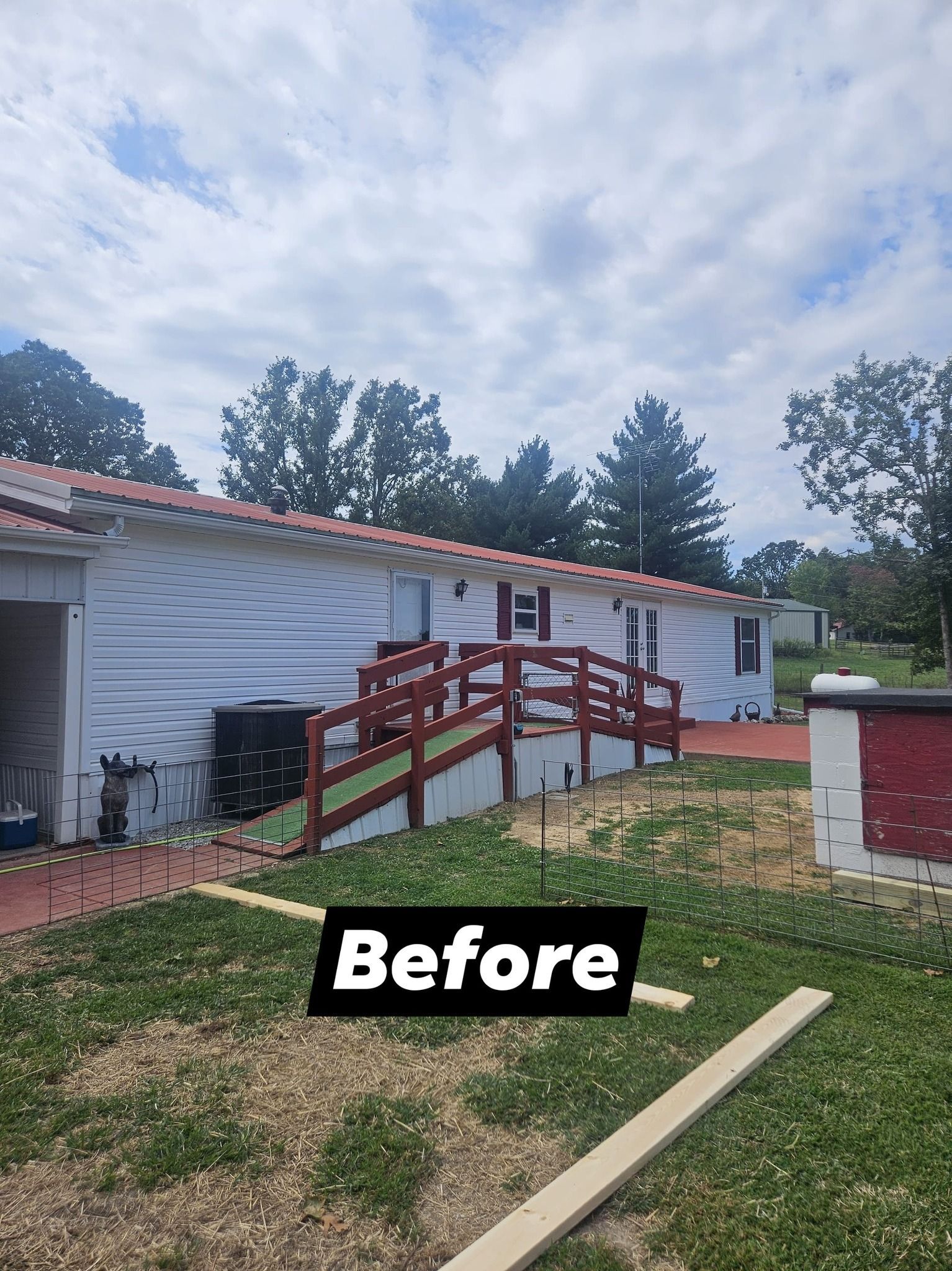 Exterior view of a building with a red ramp, red roof tiles, and white siding, set on a grassy hill.
