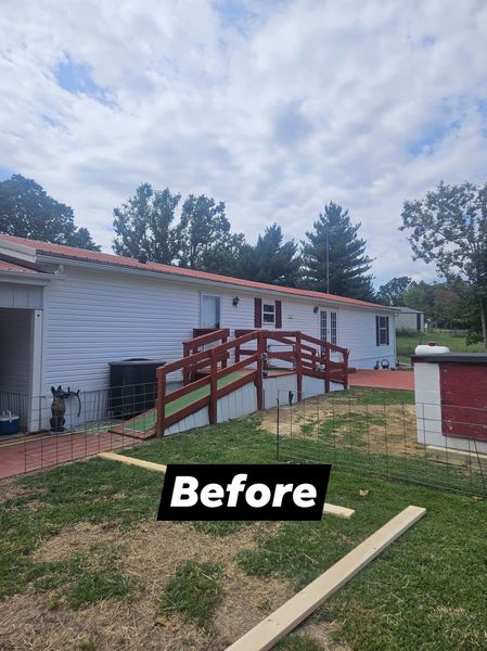 Exterior view of a building with a red ramp, red roof tiles, and white siding, set on a grassy hill.
