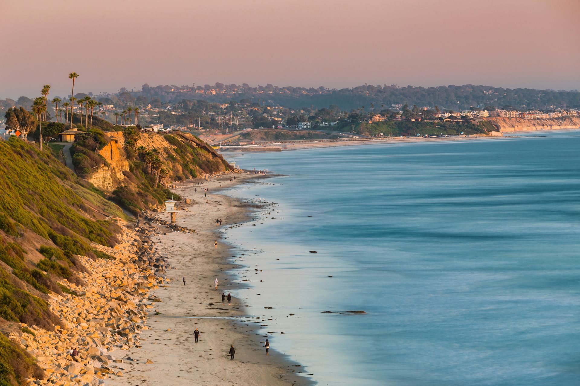 A group of people are standing on a beach near the ocean.