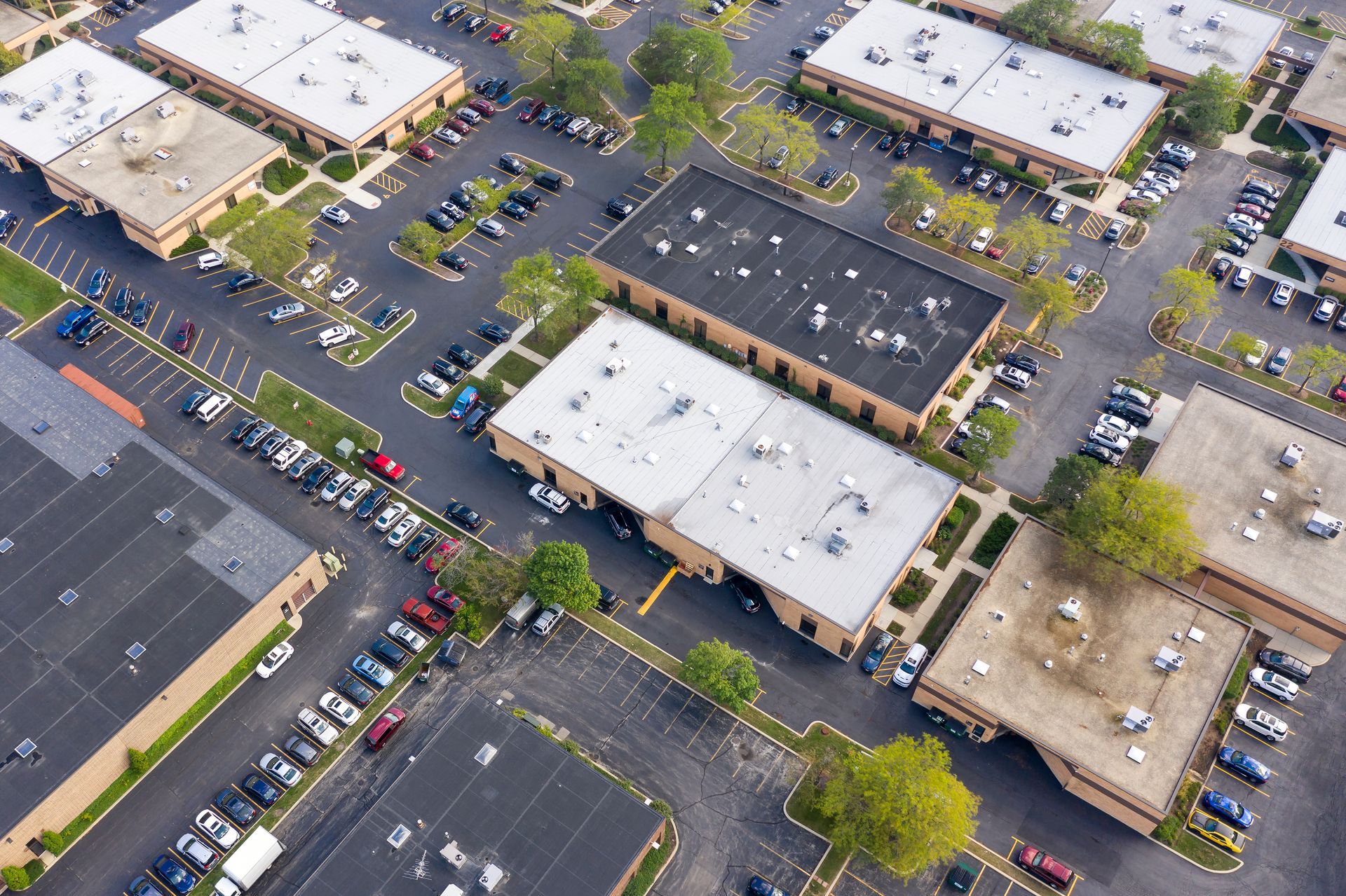An aerial view of a parking lot filled with cars and buildings.