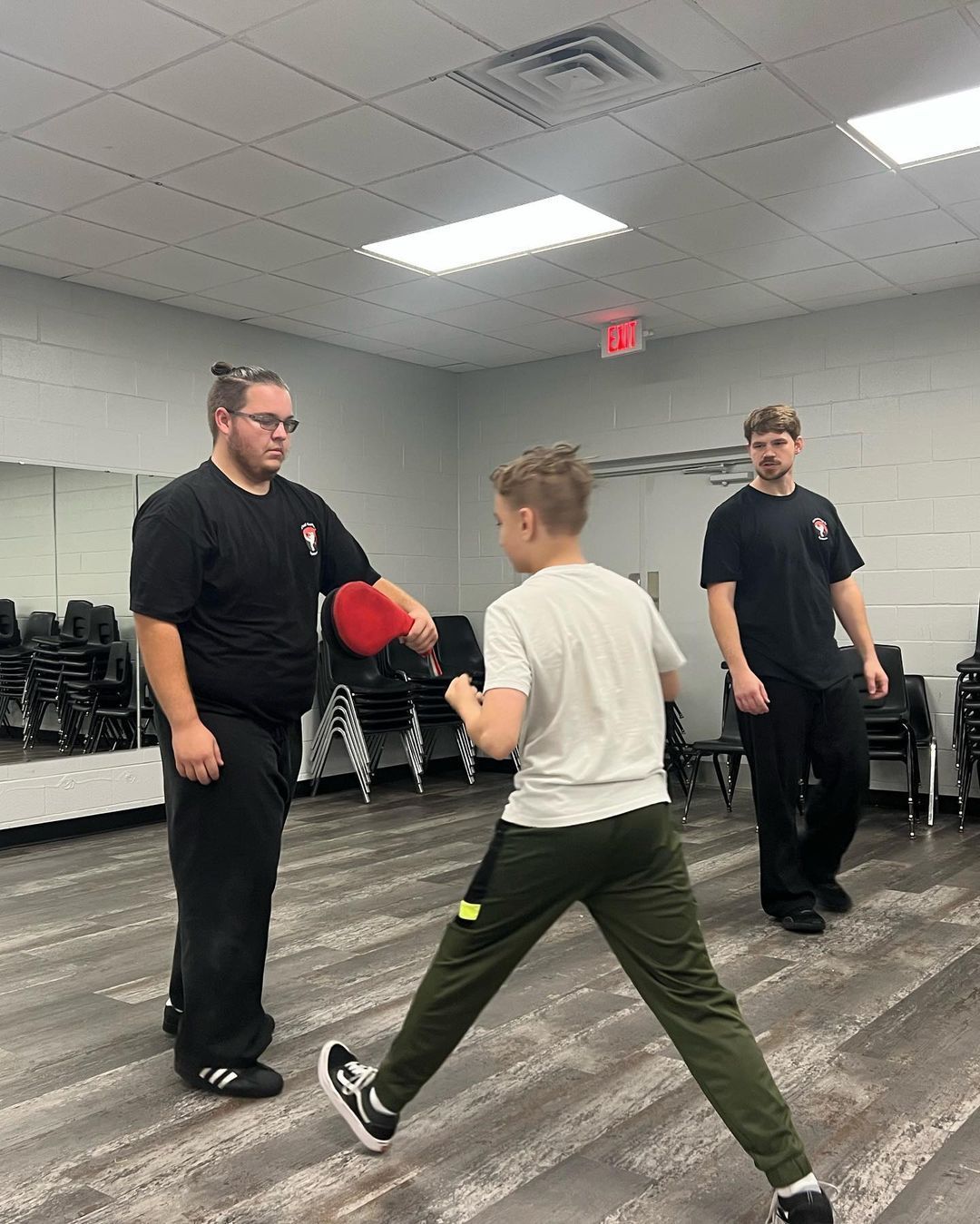 A man is teaching a young boy how to box in a gym.