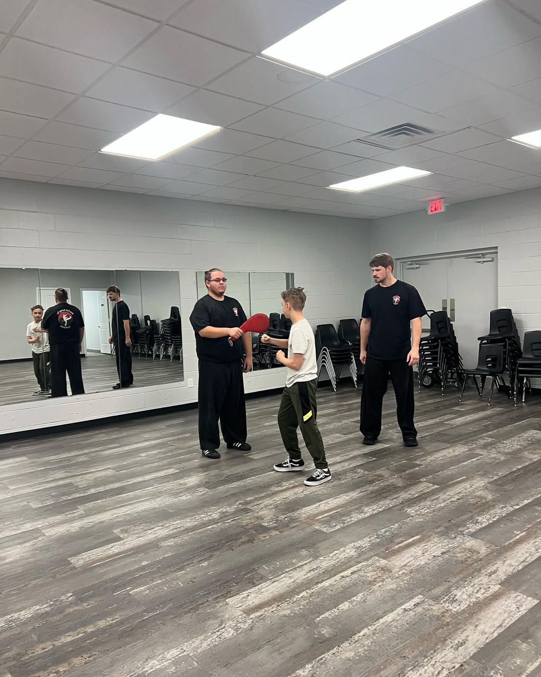 A group of people are standing in a room in front of a mirror.