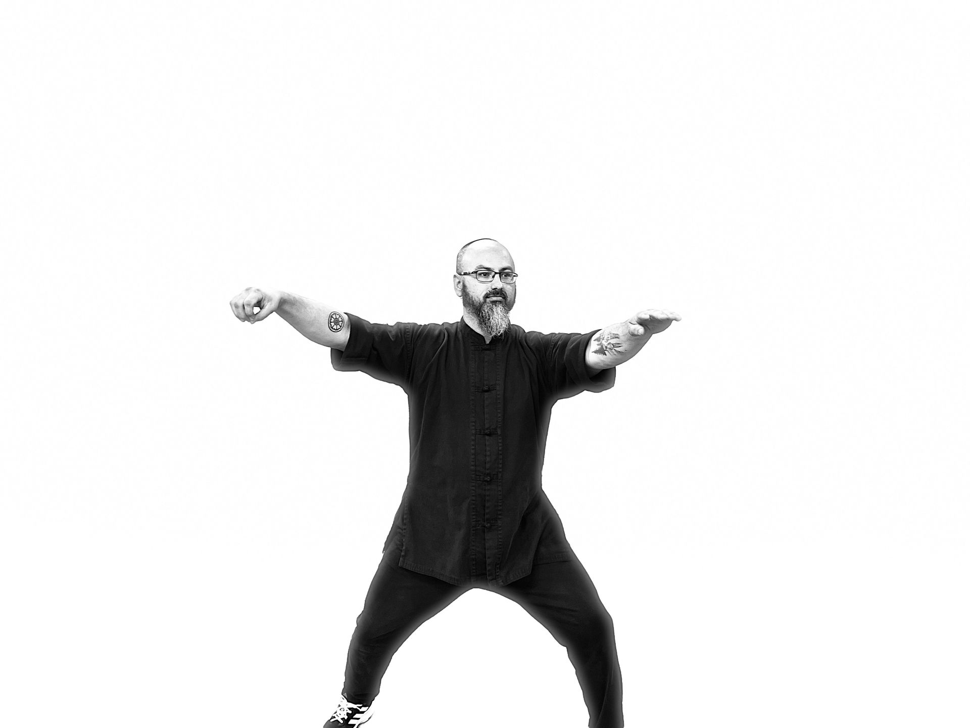 A man with a beard is standing in a black and white photo with his arms outstretched.