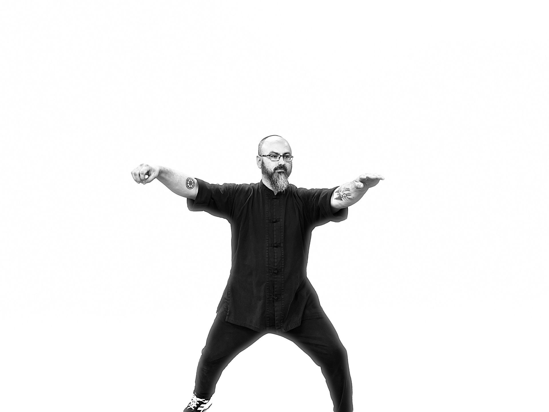 A man with a beard is dancing in a black and white photo.