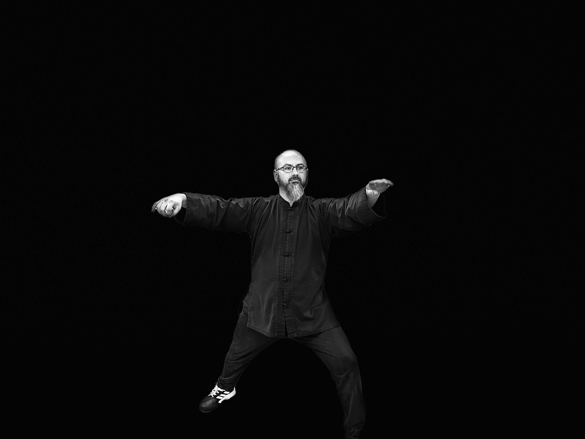 A man with a beard is dancing in a black and white photo.