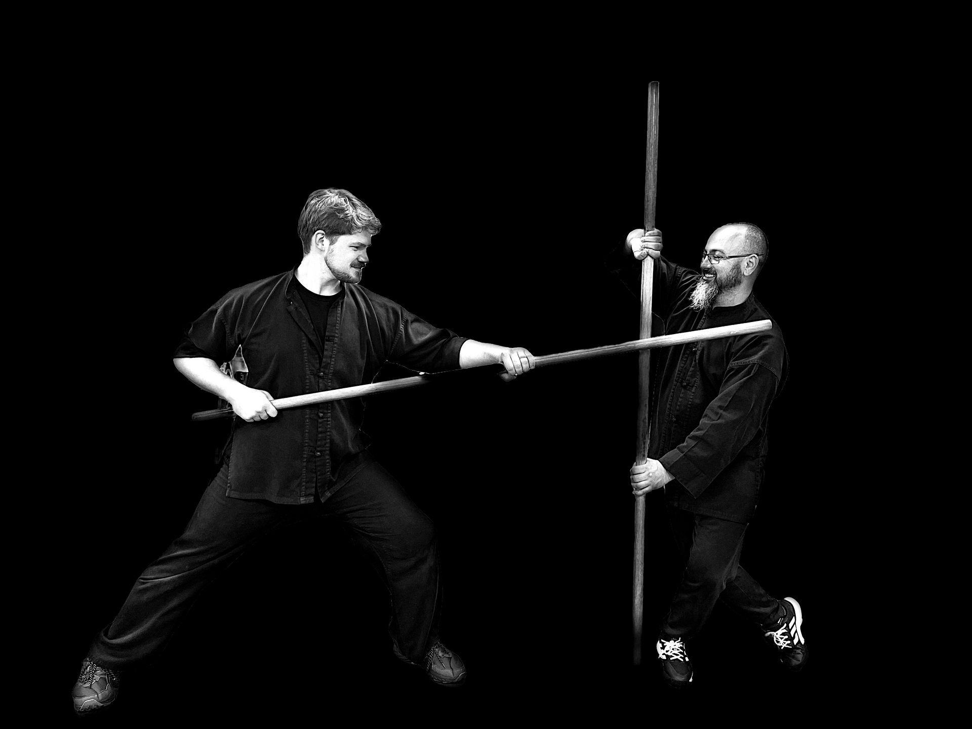 Two men are fighting with poles in a black and white photo.
