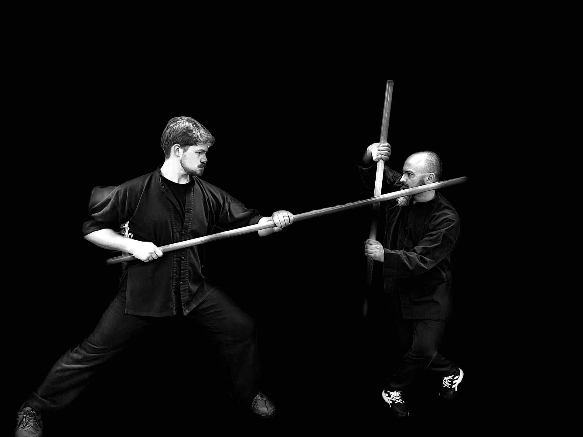 Two men are holding sticks in their hands in a black and white photo.
