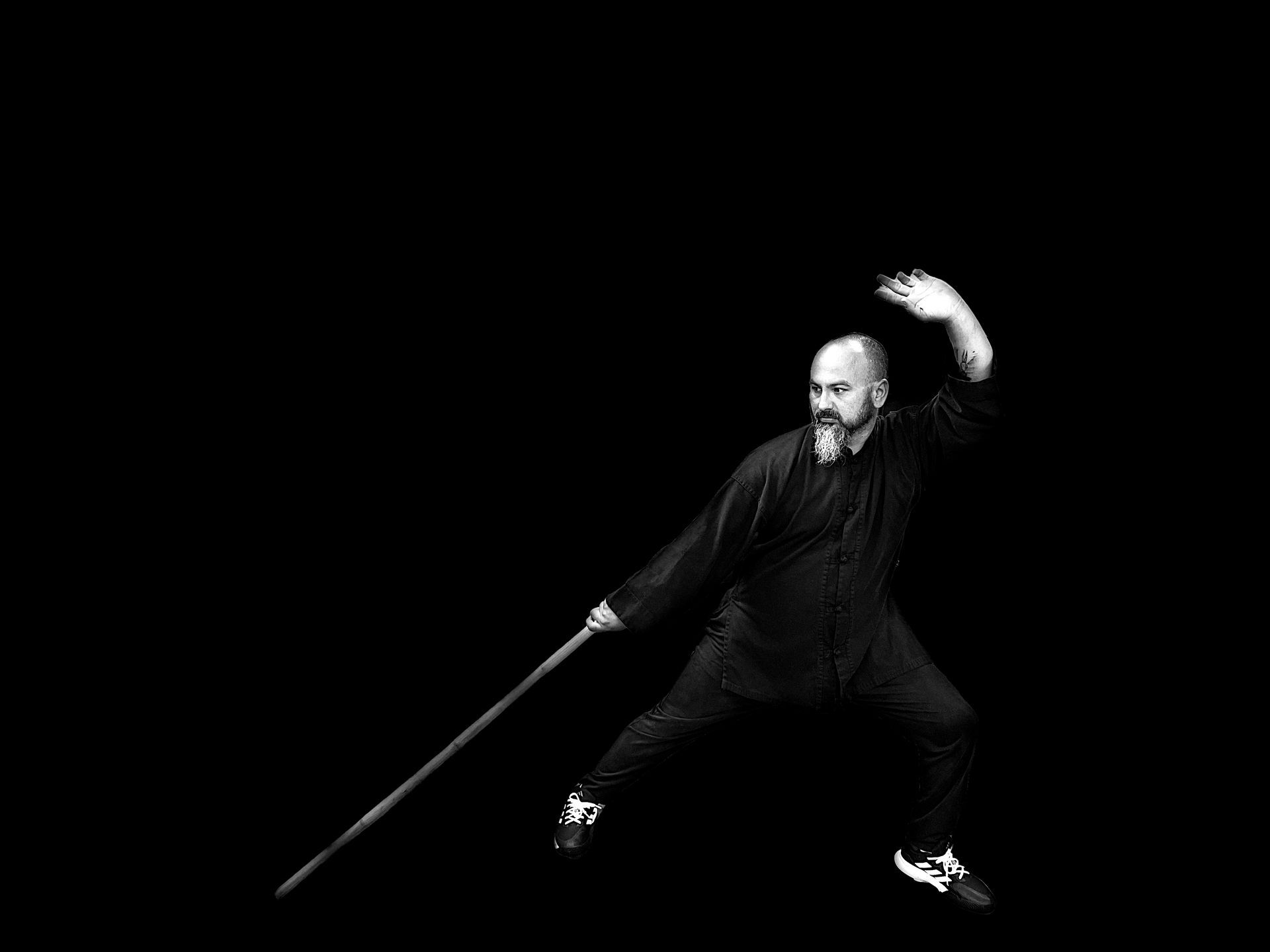 A man is holding a long stick in his hand in a black and white photo.