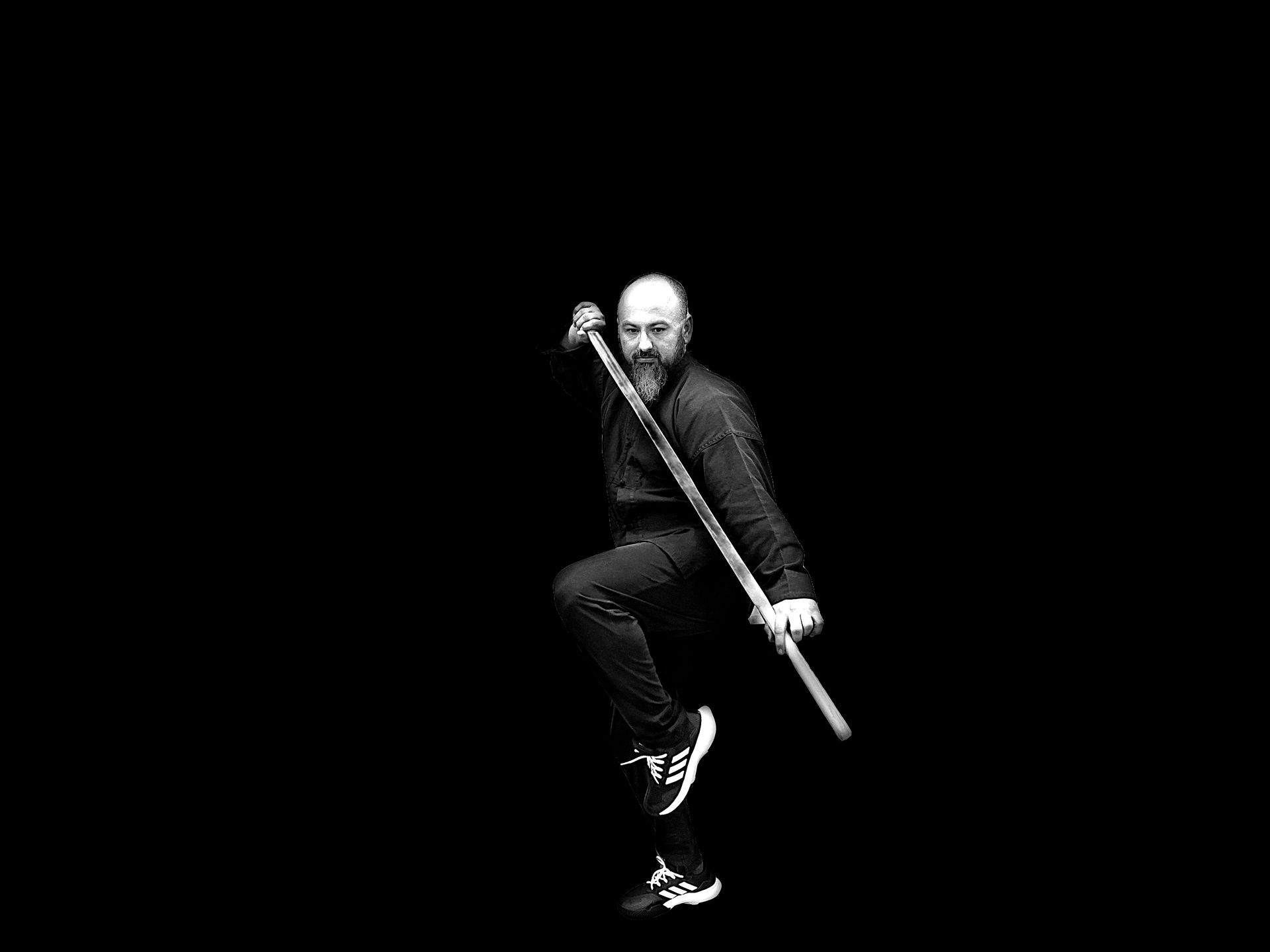 A man is holding a stick in his hand in a black and white photo.